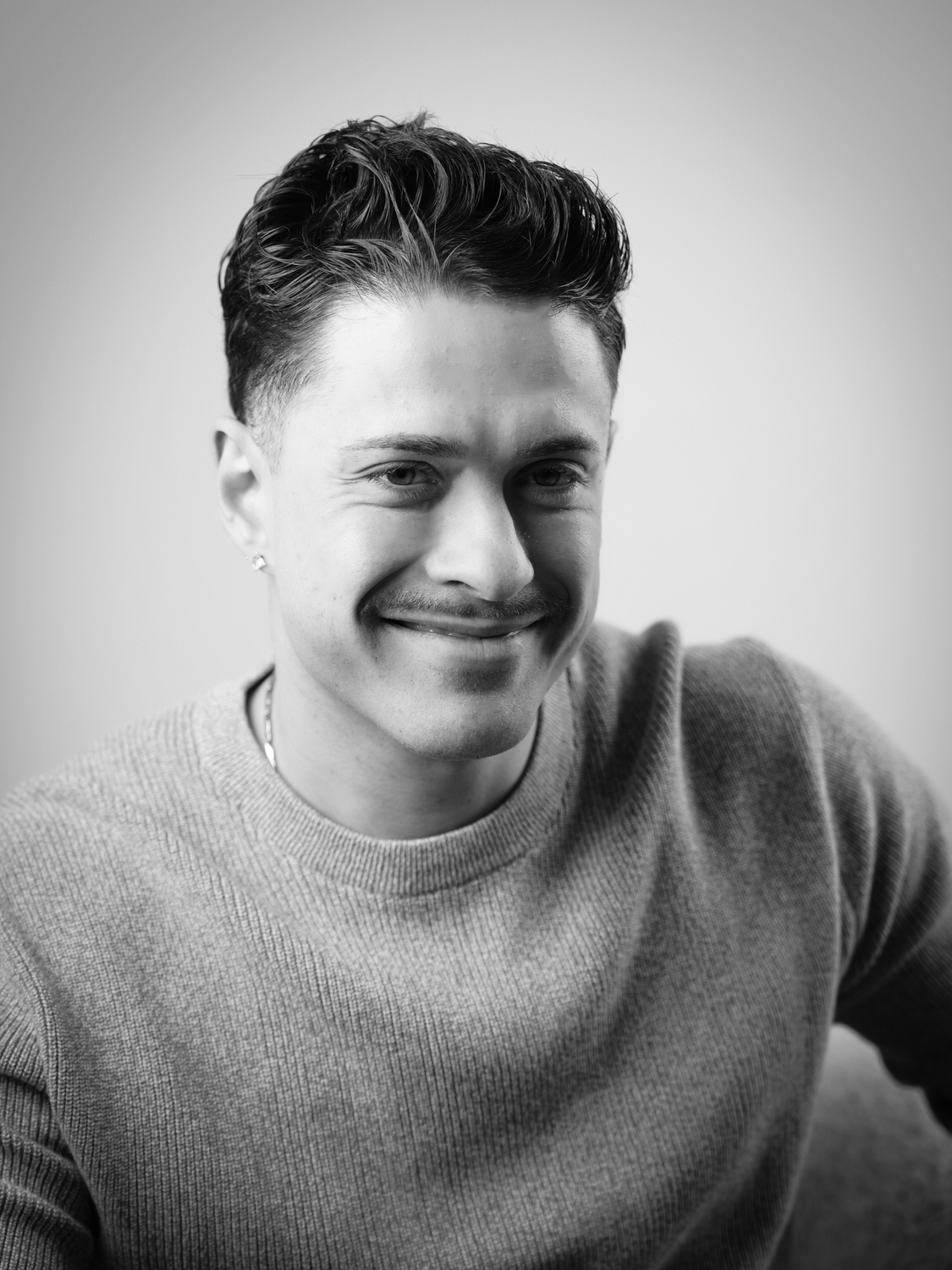 Mann lächelt in die Kamera bei Porträtaufnahme, seitlicher Blick, schwarz-weiss, Fotograf Aachen