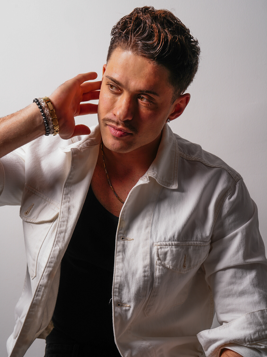 Männliches Model posiert im Studio, heller Hintergrund, Hand am Ohr, Fotograf Aachen