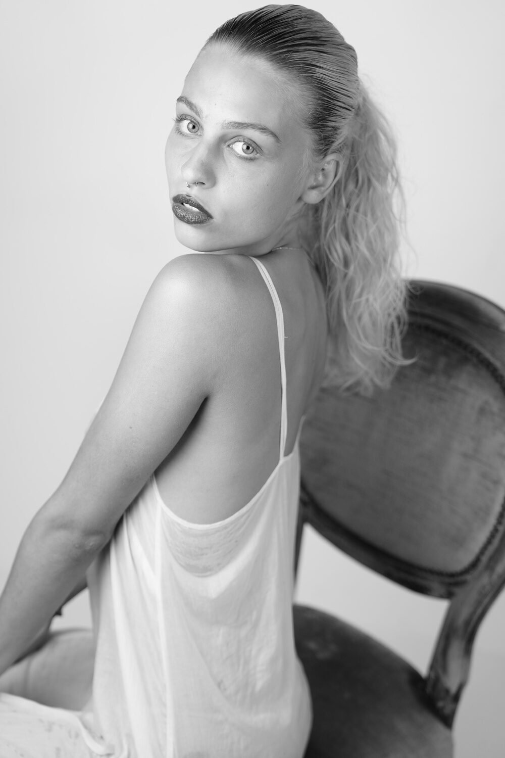 Dessous-Fotoshooting, Act-Fotografie, schwarz-weiss-Foto, seitlich sitzend auf einem Stuhl, Fotograf Aachen