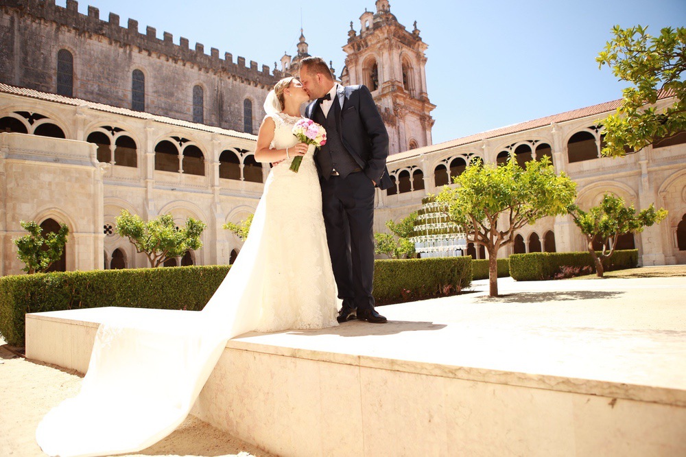 Brautpaar beim Kuss im Innenhof der Kirche mit Bäumen im Hintergrund, Hochzeitsfotograf Aachen