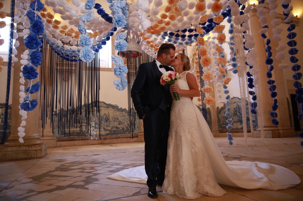 Brautpaar beim Kuss in der Kirche mit bunten Blumen, die von der Decke hängen, Hochzeitsfotograf Aachen